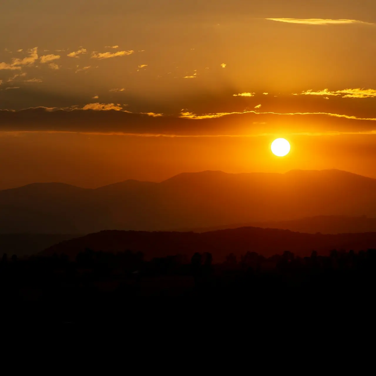 the sun is setting over a mountain range